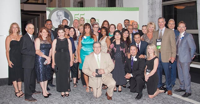 A group of Licensed Operators pose in front of a photo backdrop.