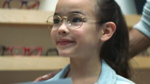 little girl in cute glasses with a slight smile