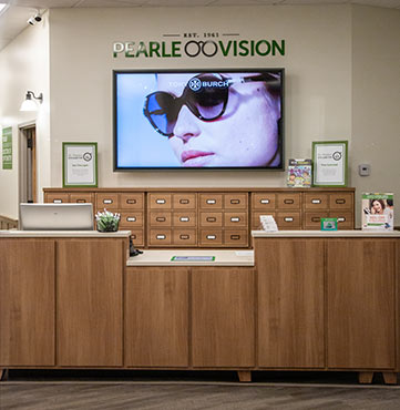 Tory Burch image on a television behind a check out area inside a Pearle Vision franchise