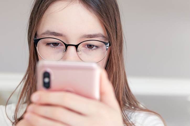 young girl in glasses looking at a phone